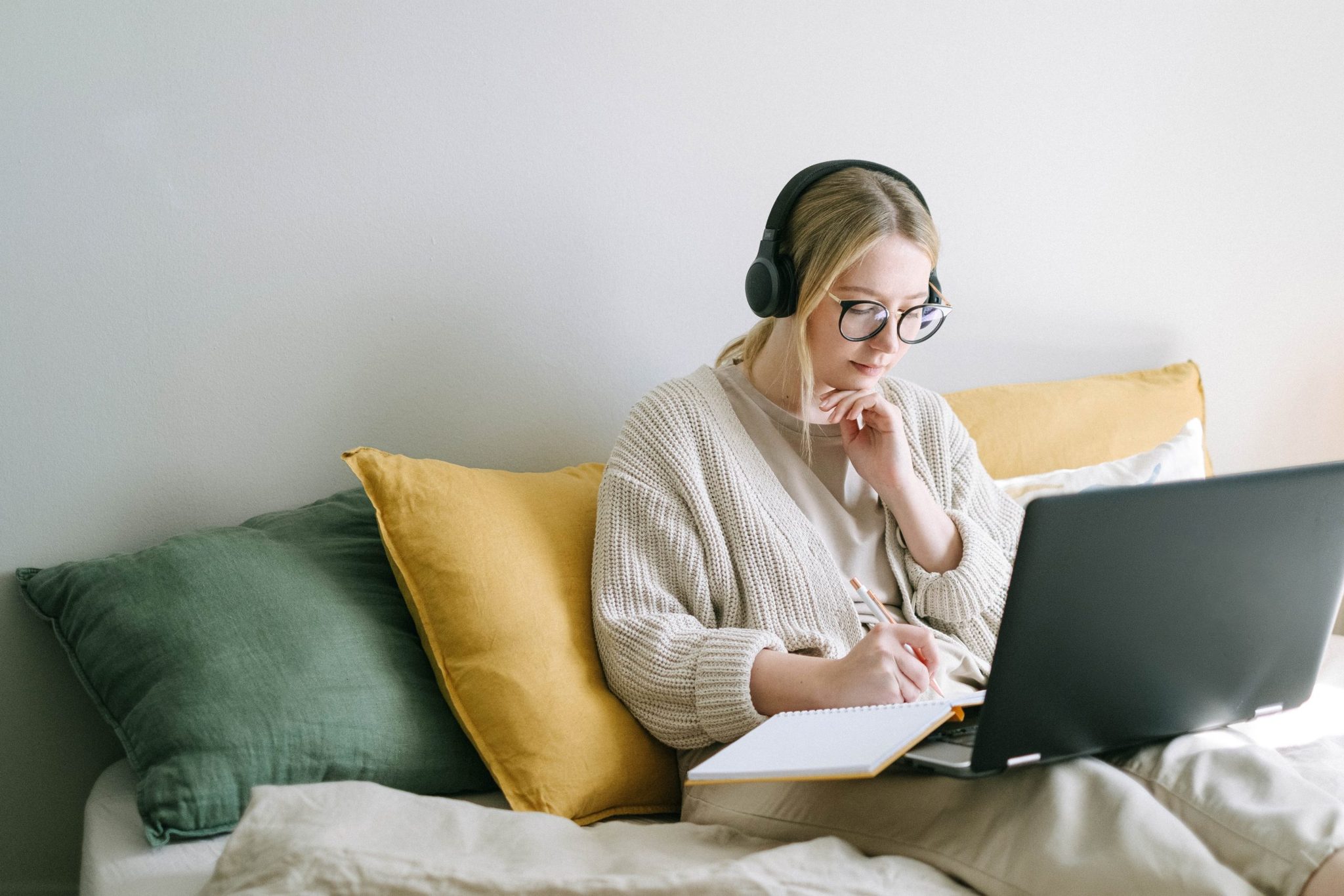 lady writing in a notebook with her laptop open