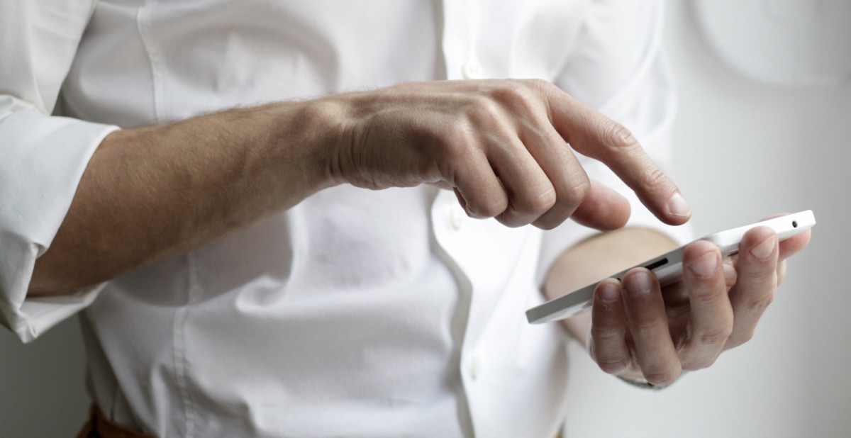 A hand tapping the screen of a smartphone, the way customers use a bank's mobile app