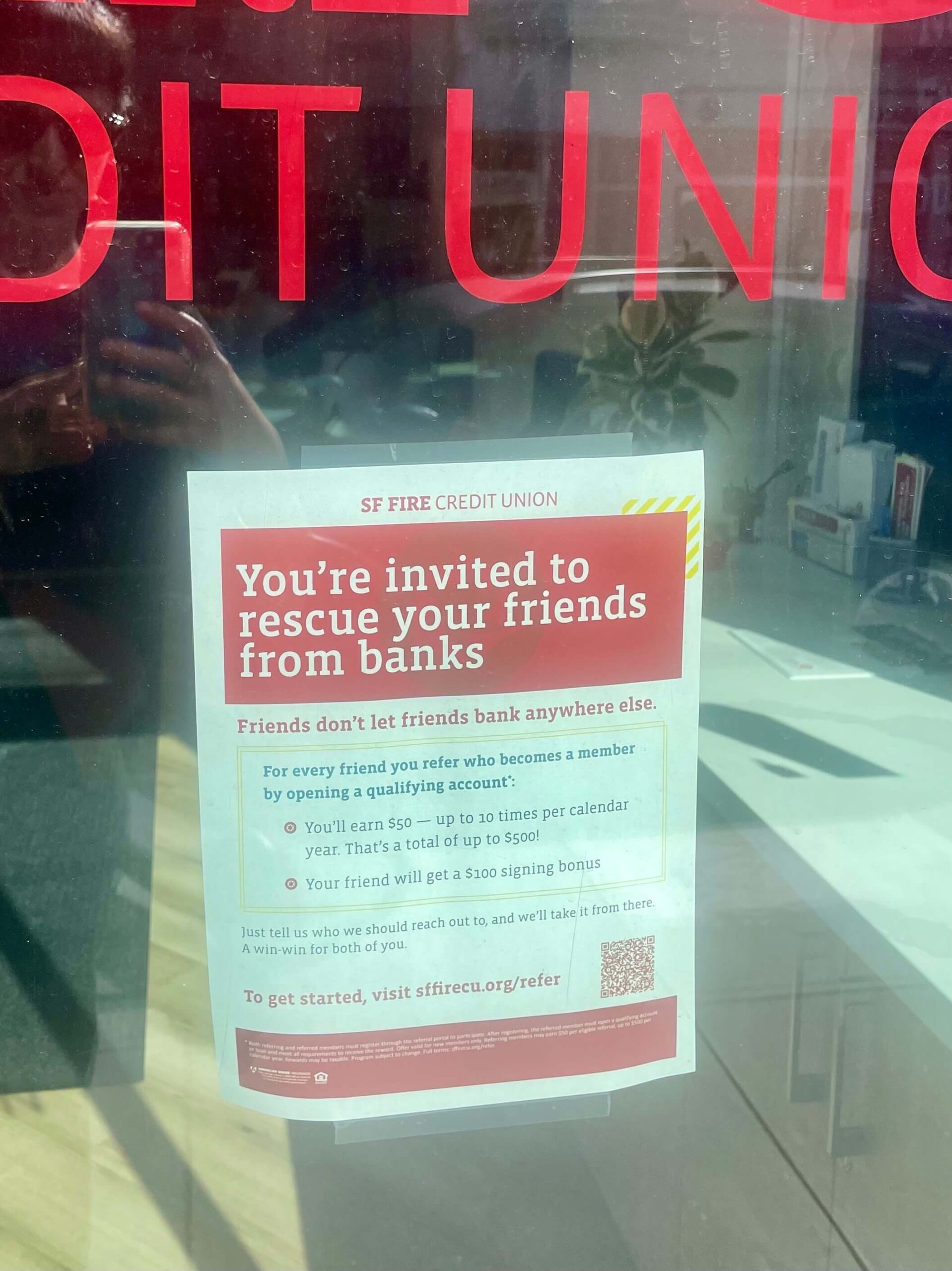SF Fire Credit Union referral program example displayed on a storefront flyer, offering members $50 for each friend who opens a qualifying account, up to $500 per year, while the referred friend receives a $100 signing bonus.