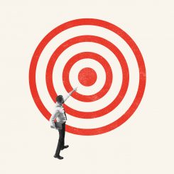 Businessman reaching toward a red bullseye target on a light background, symbolizing aiming for a goal.